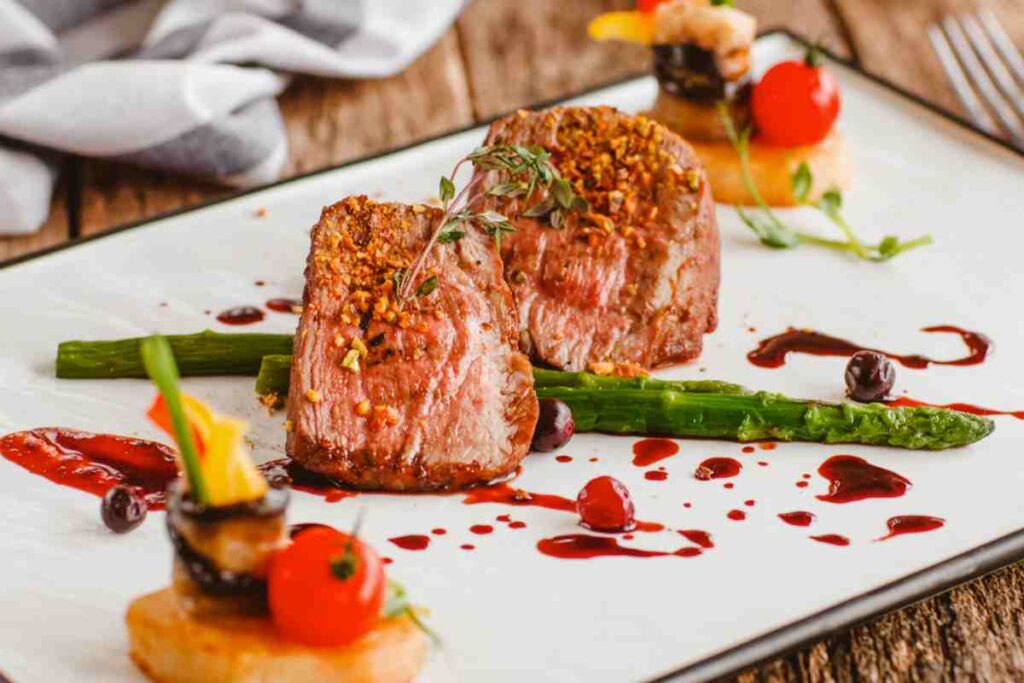 un piatto gourmet con carne ed asparagi decorato con salse