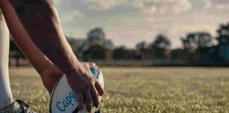 mani di un giocatore di rugby che posizionano la palla ovale