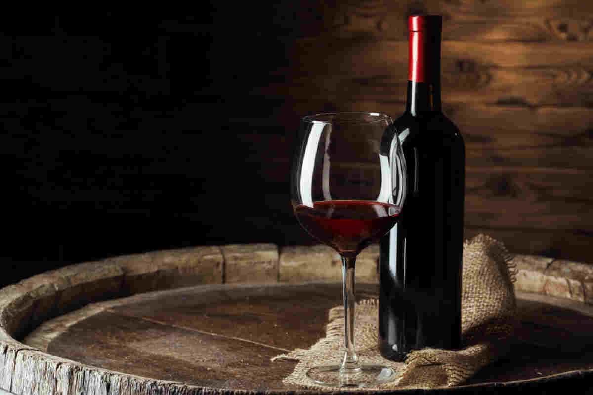 bicchiere e bottiglia di vino rosso su una botte