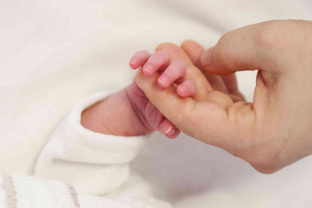 donna che tiene la mano di un neonato