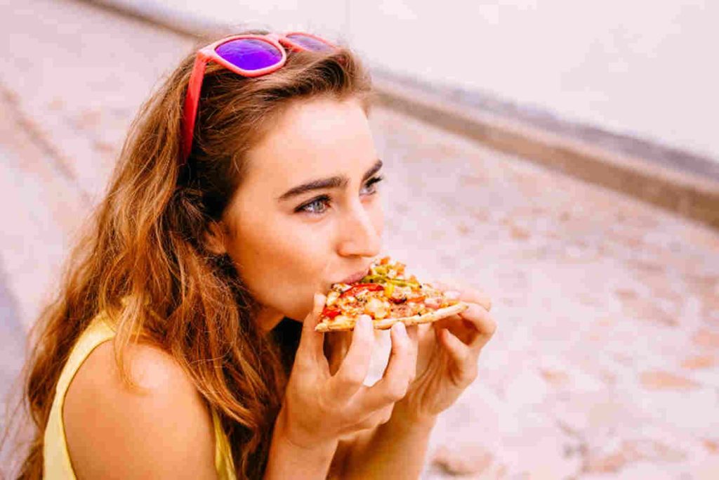 ragazza che mangia la pizza per strada