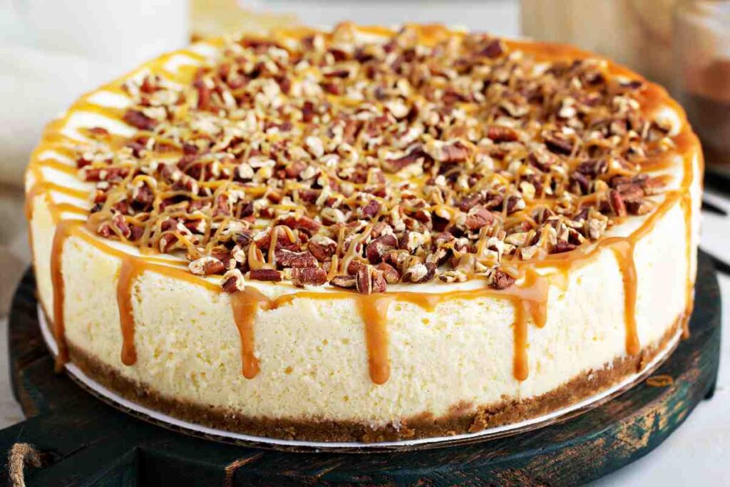 Cheesecake light al caramello salato coperta di noci pecan su un tagliere