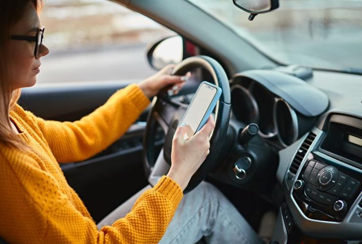 Automobilista con telefono in mano alla guida