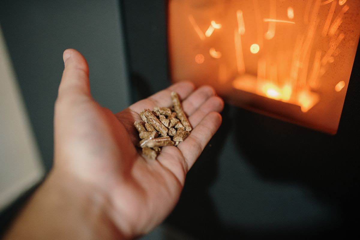 Pellet sul palmo della mano e stufa accesa