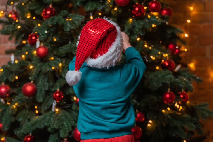 Bmbino che tocca le palline sull'albero di natale