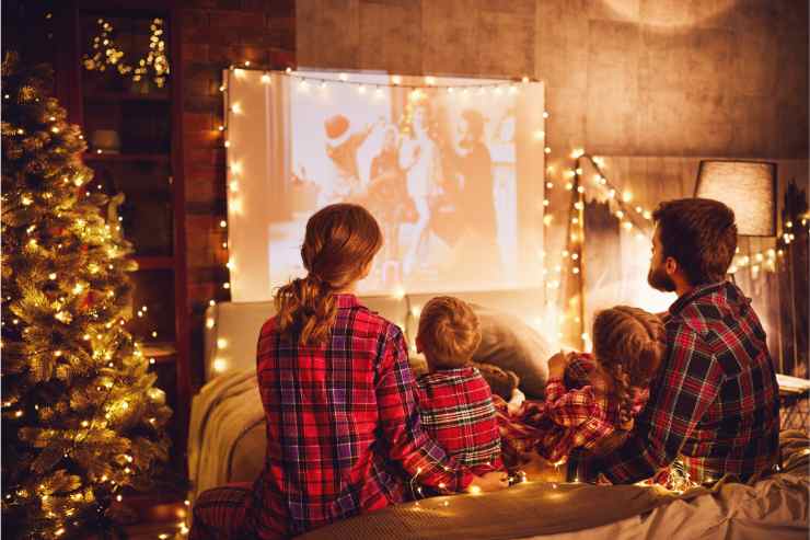 famiglia davanti allo schermo in casa addobbata per Natale