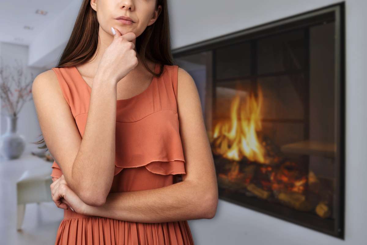 donna dubbiosa con caminetto elettrico alle spalle