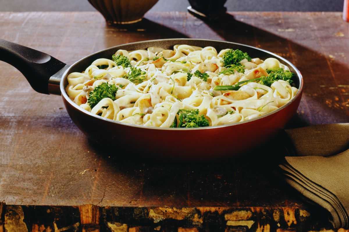 Una pentola con dentro delle fettuccine e dei broccoli