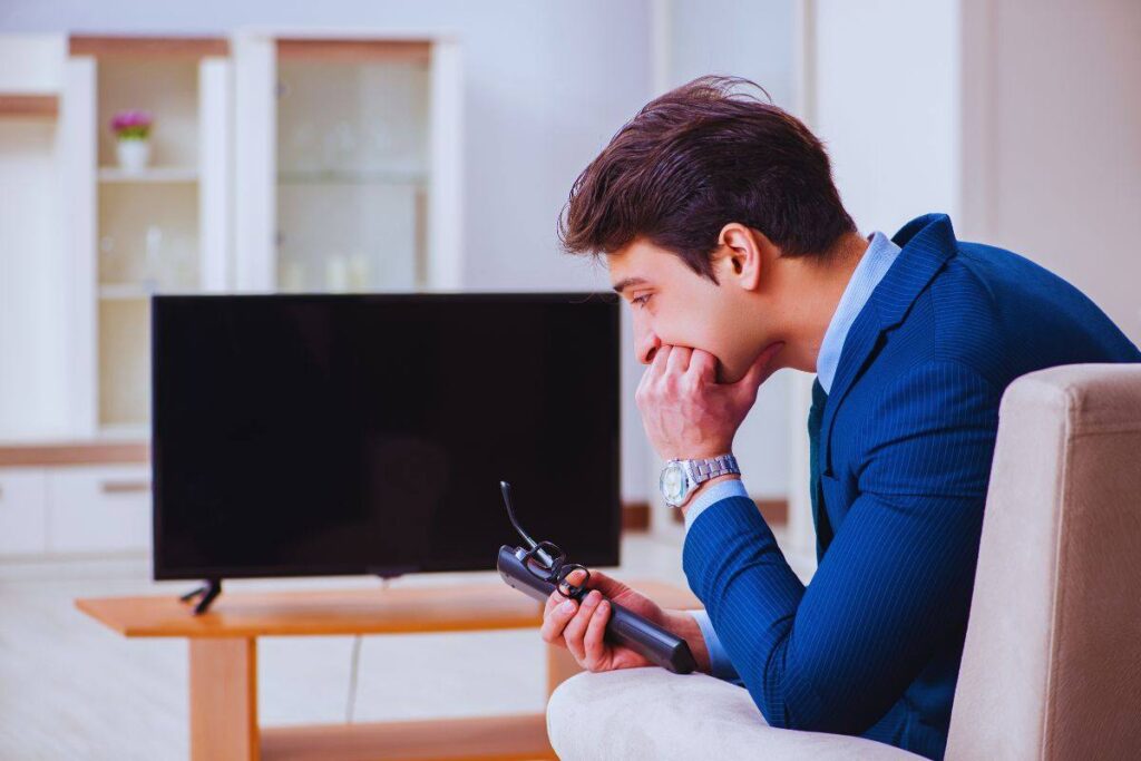 Uomo afflitto davanti a tv spenta