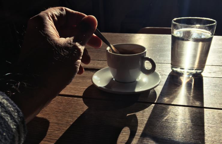 tazzina di caffè con mano che mescola