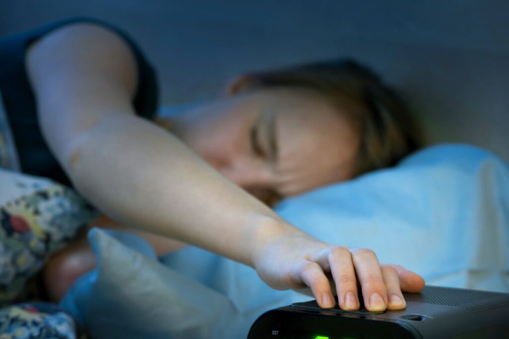 Donna a letto che allunga la mano sulla sveglia