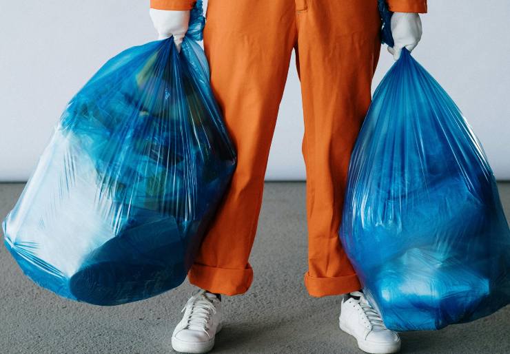 gambe di uomo che tiene regge buste della spazzatura