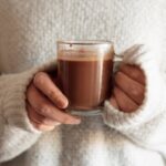 Donna stringe tra le mani una tazza di cioccolata calda