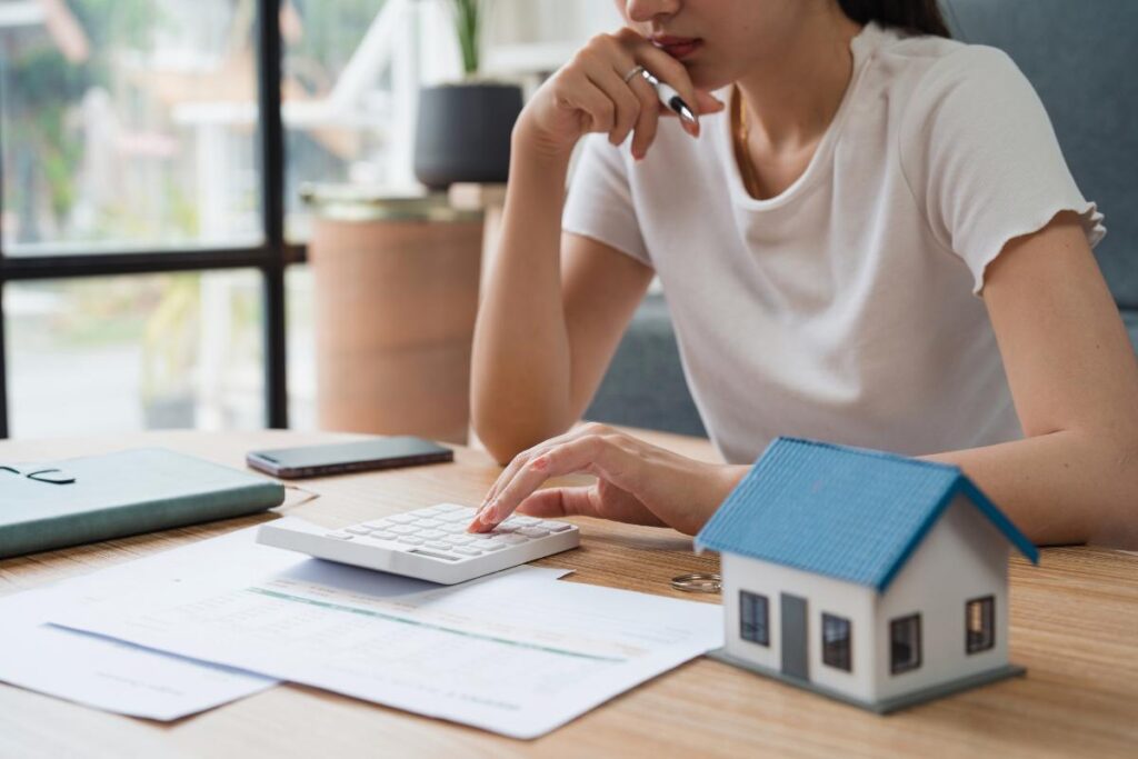 donna alla scrivania con modellino casa e documenti