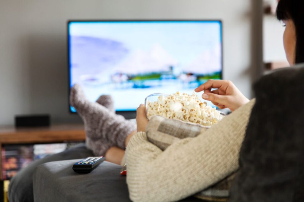 donna in poltrona che guarda la tv con popocorn