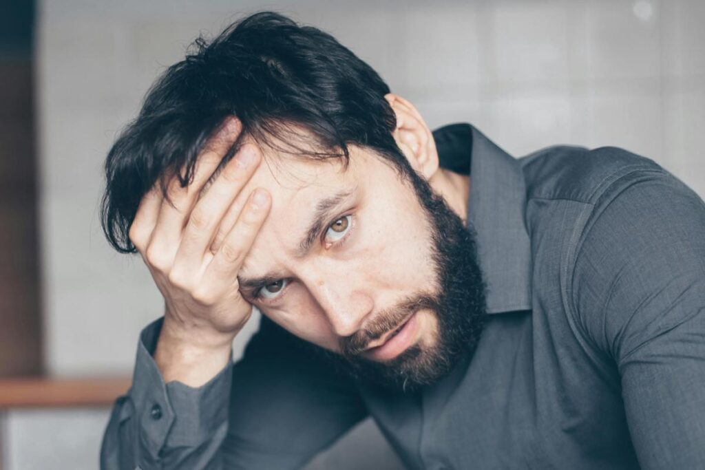 uomo preoccupato con una mano sulla fronte