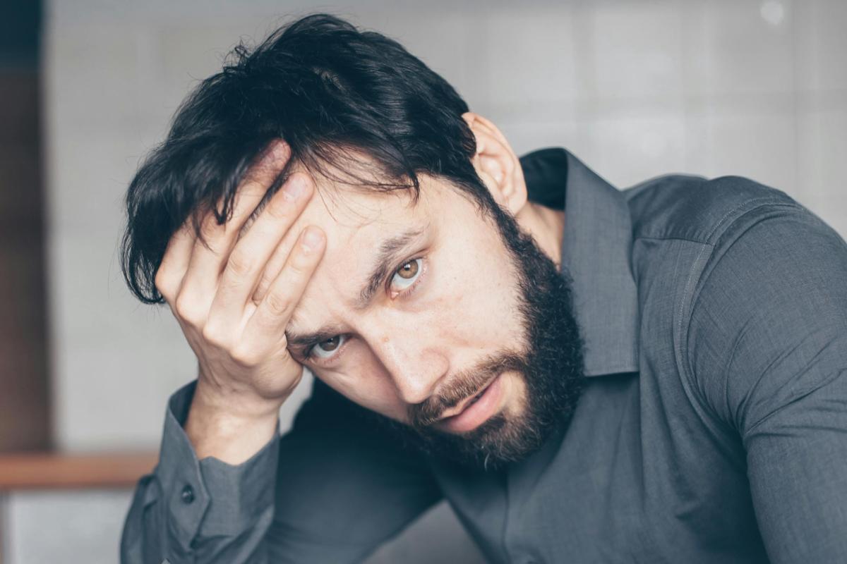 uomo preoccupato con una mano sulla fronte