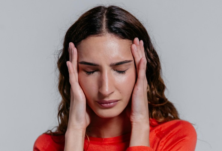 donna preoccupata con gli occhi chiusi e le mani sulle tempie vestita di rosso