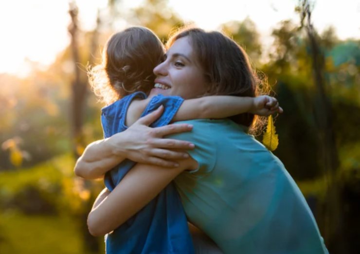 madre che abbraccia la figlia in un parco