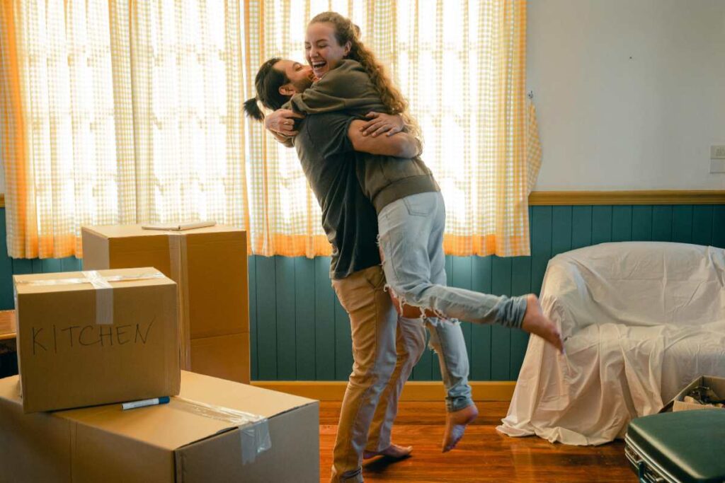 uomo che prende in braccio una donna dentro casa in mezzo agli scatoloni