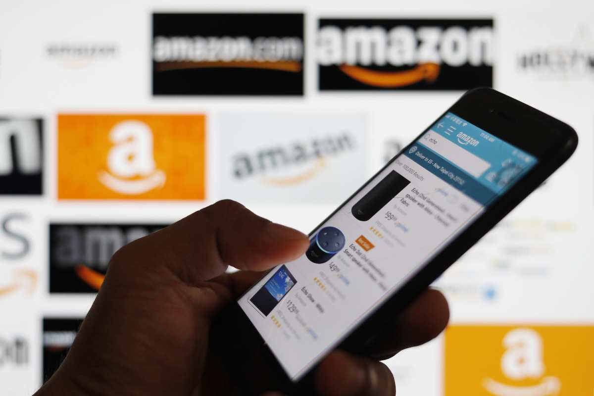 Loghi Amazon e persona che scorre lo store su iPhone