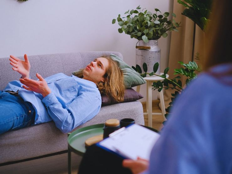 uomo sdraiato su divano si confida con lo psicologo