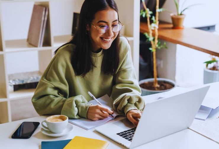 Ragazza sorride mentre lavora al PC