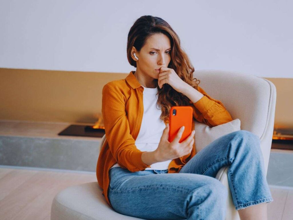 Donna con espressione preoccupata mentre guarda qualcosa sullo smartphone