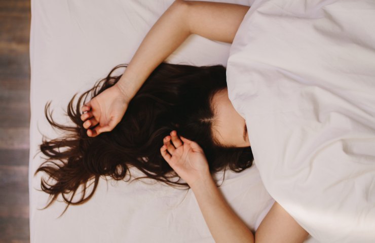 donna a letto nascosta dalle lenzuola