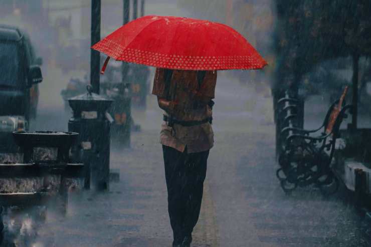 Donna cammina sotto la pioggia protetta dall'ombrello