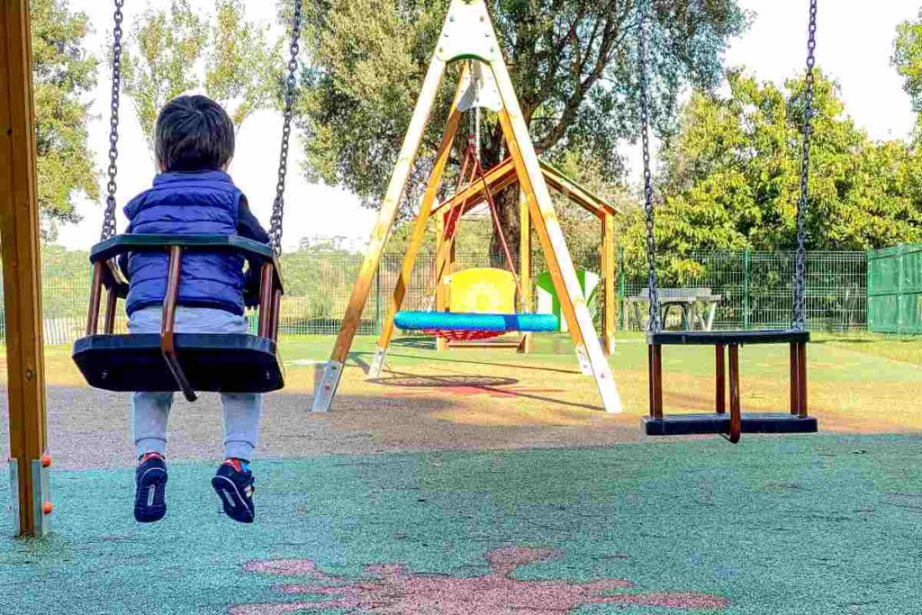 bambino al parco sull'altalena di spalle