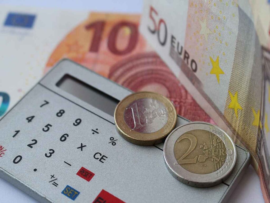 calcolatrice con sopra monete di euro e intorno delle banconote
