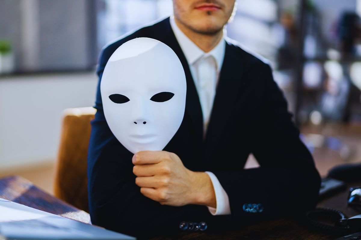 Uomo in abito elegante che tiene in mano una maschera