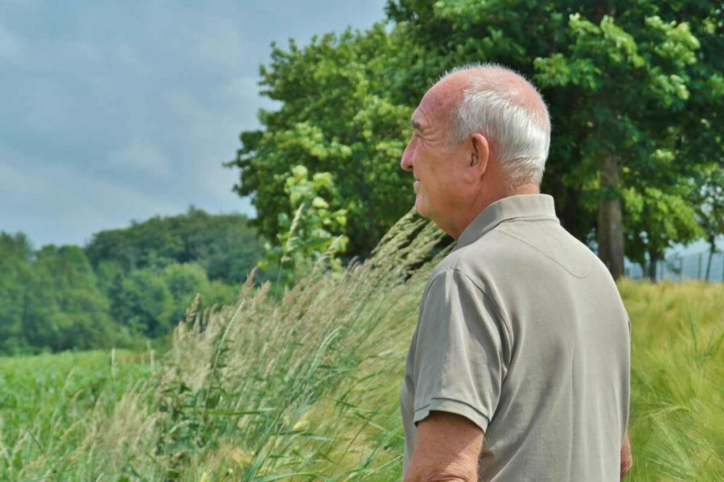 uomo di profilo che sorride e guarda lontano in mezzo alla natura