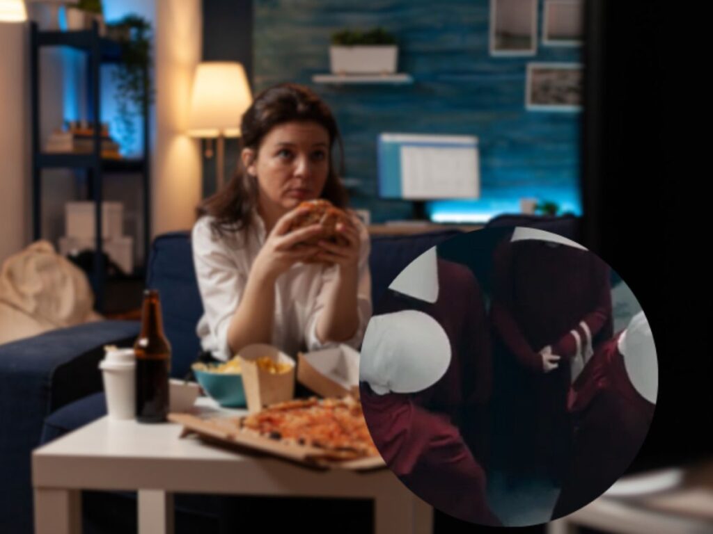 donna che guarda la tv mentre mangia una pizza