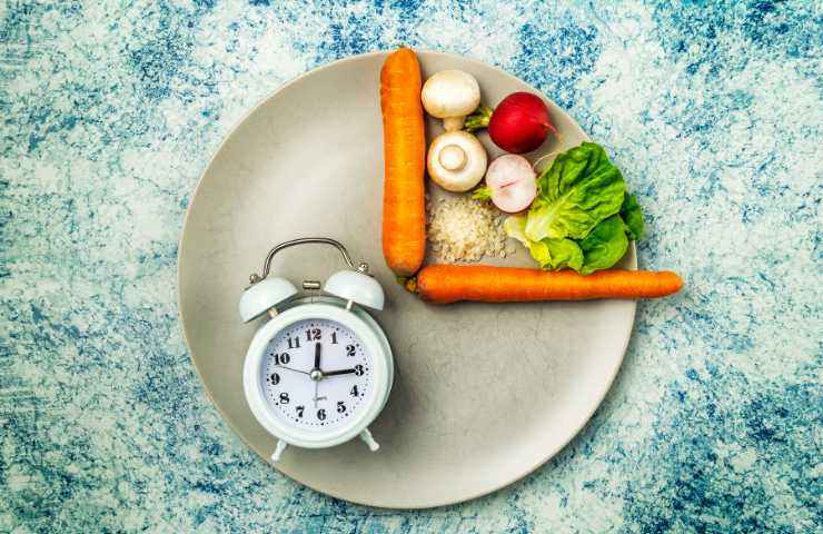 Piatto con alimenti e una sveglia