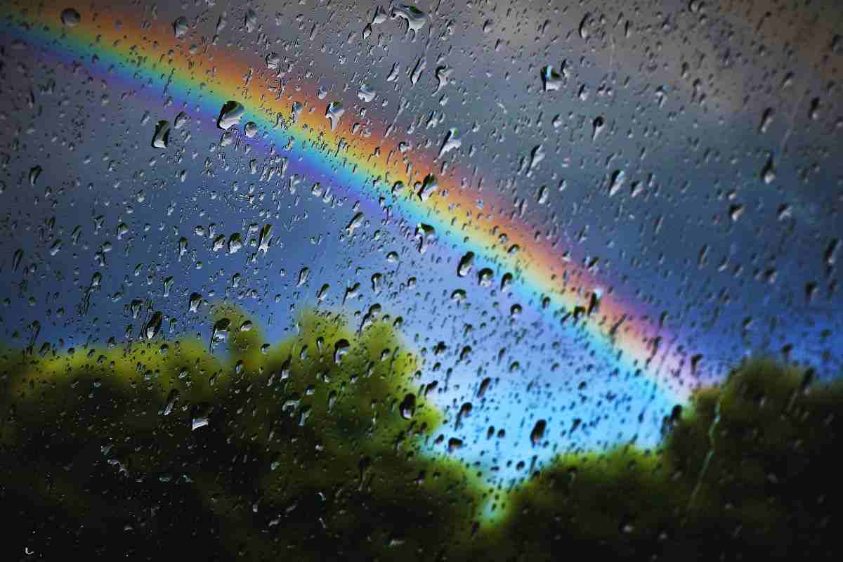 Arcobaleno visto attraverso finestra bagnata dalla pioggia