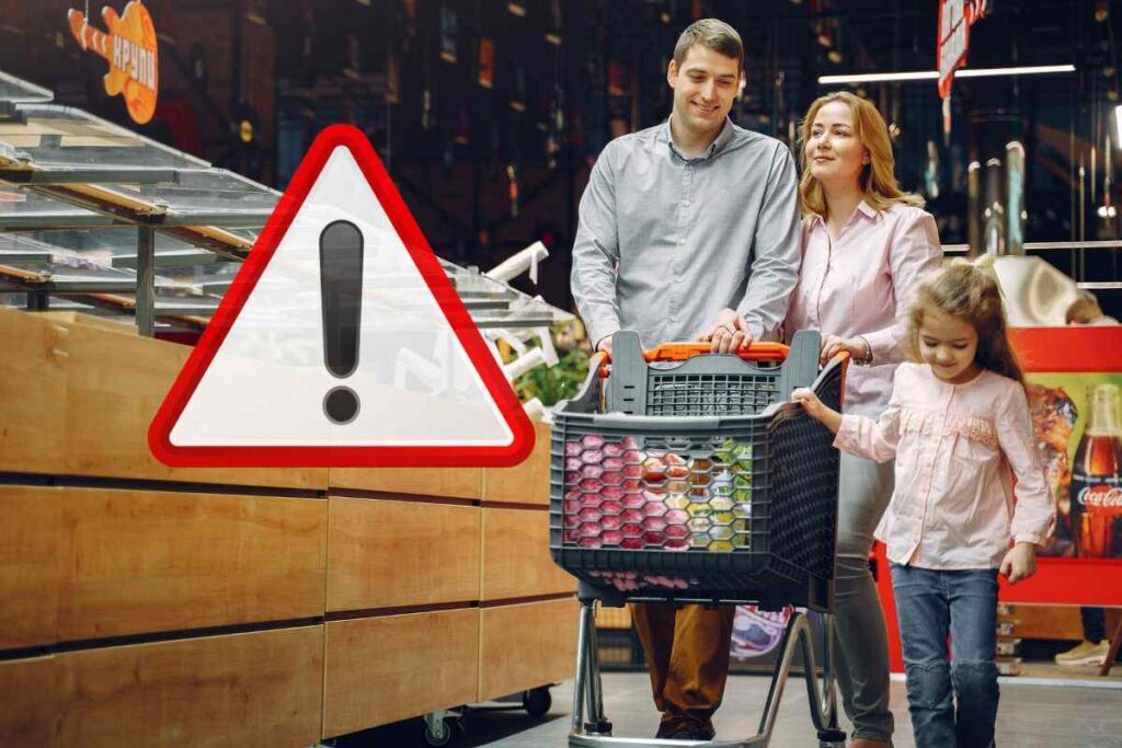 coppia con bambina col carrello e segnale di pericolo