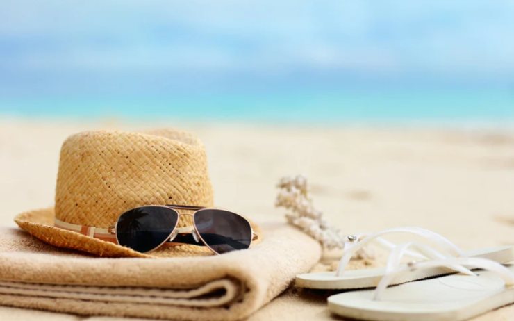 cappello e occhiali con telo su una spiaggia