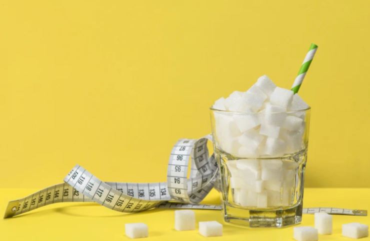 bicchiere pieno di zucchero e metro a nastro