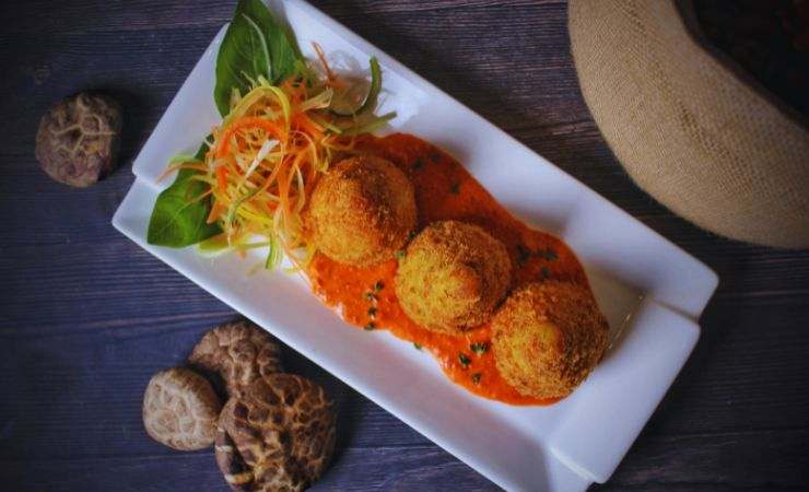 pallotte nel sugo e in un piatto rettangolare con insalatina e basilico