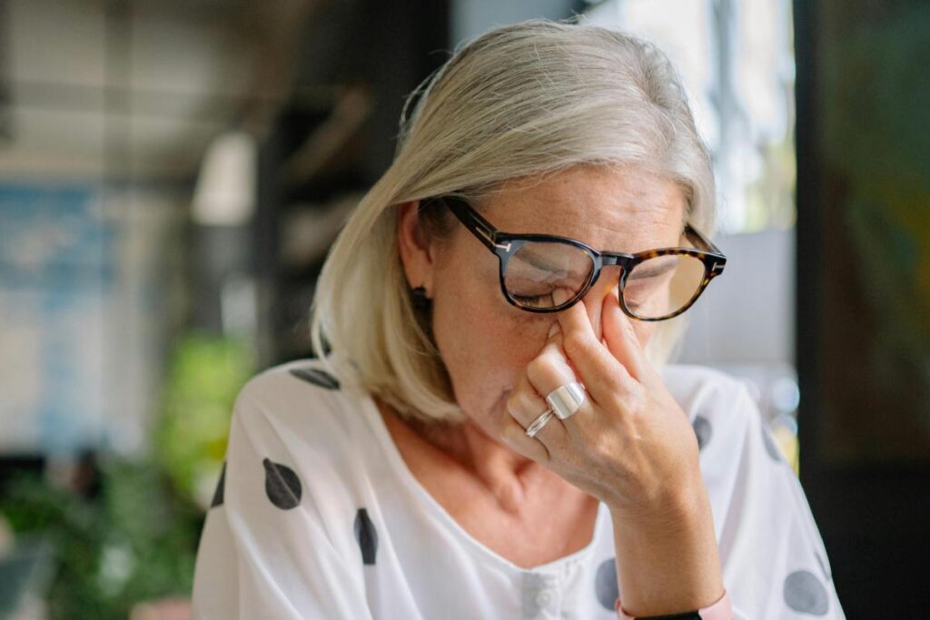 donna con gli occhi chiusi che con le dita si tocca il naso in alto