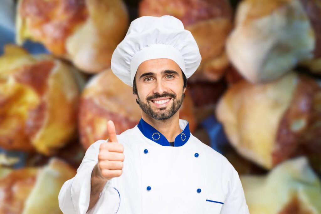 Chef in primo piano che fa segno ok e fiadoni da sfondo