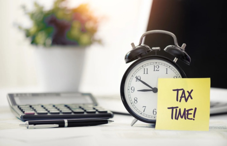 sveglia accanto ad una calcolatrice e un foglietto con scritto "tempo di tasse"