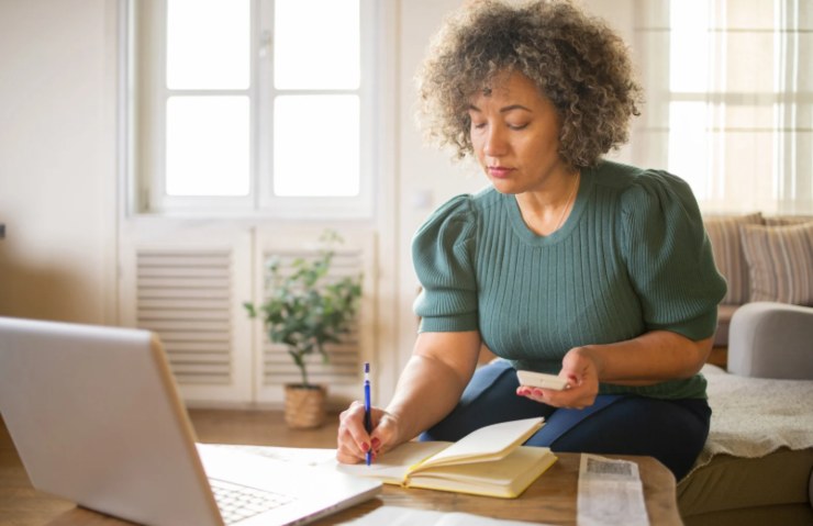donna davanti al computer che scrive su un quaderno