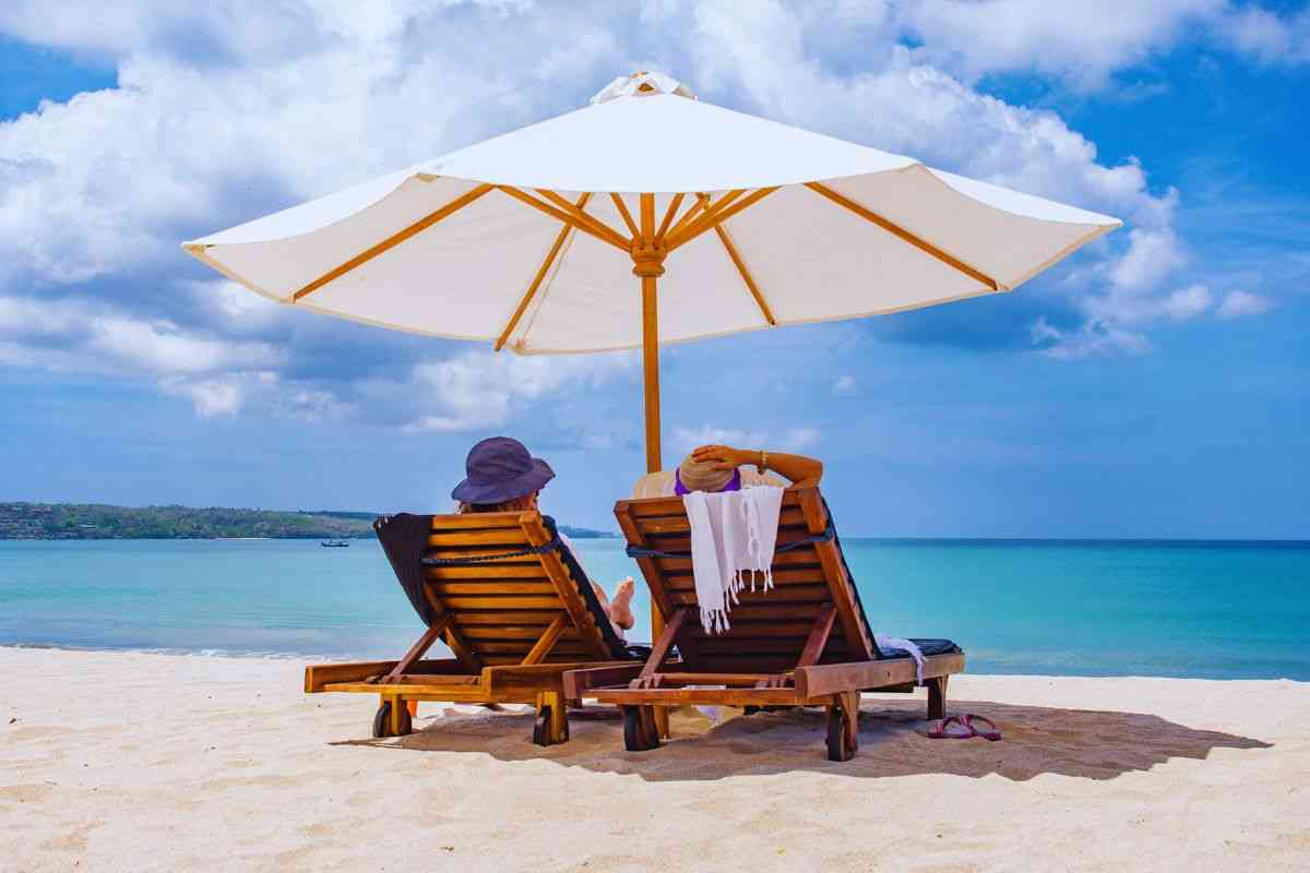 Due persone sdraiate sotto l'ombrellone in spiaggia