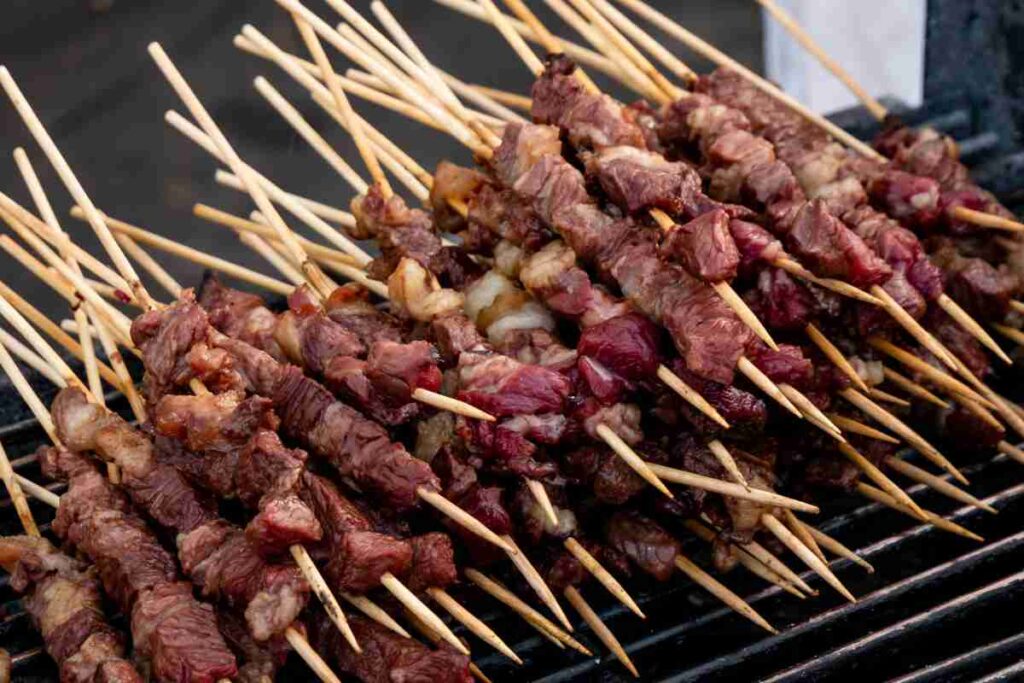 tanti arrosticini impilati su una graticola