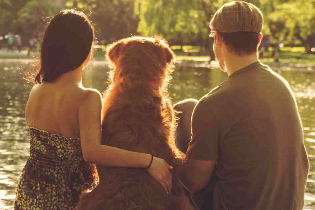 coppia abbraccia un cane in riva al lago