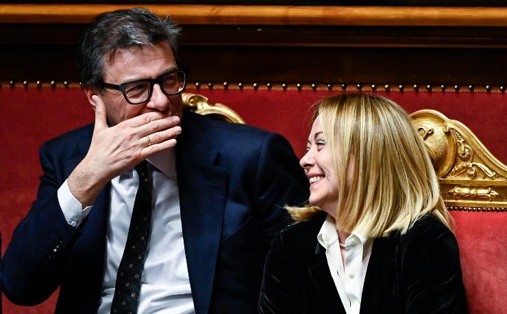 giorgia meloni che ride seduta accanto al ministro dell'economia giancarlo giorgetti