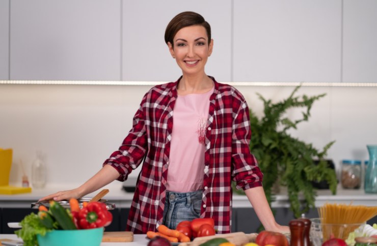 donna sorridente in cucina e sul tavolo degli ortaggi